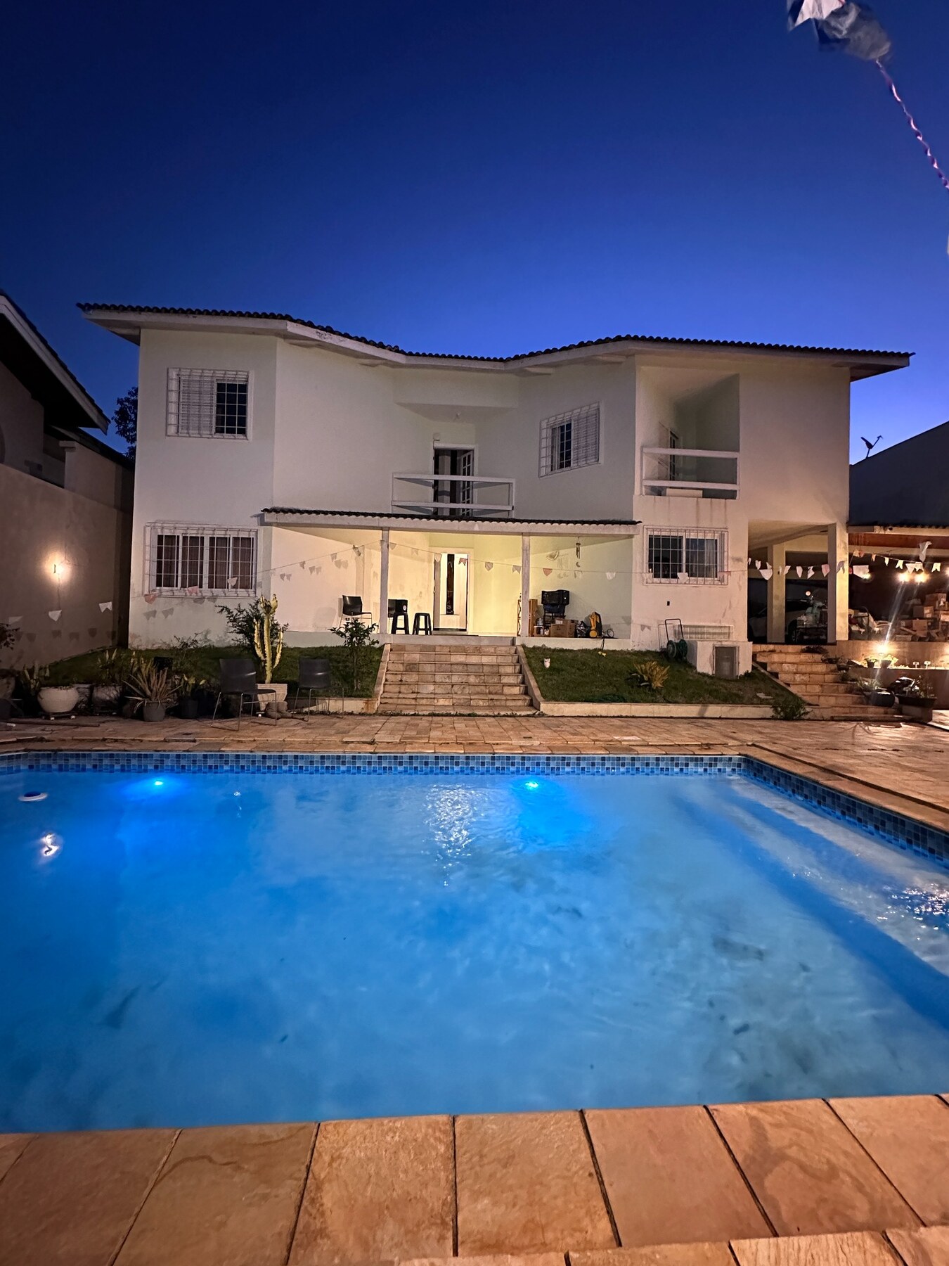 Piscina iluminada e fachada ao anoitecer