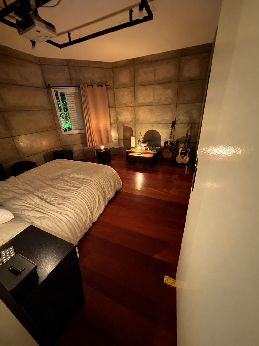 Quarto com piso de madeira, instrumentos e iluminação acolhedora